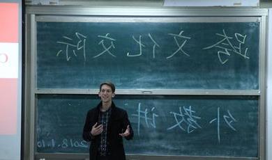 A man stands in front of a chalkboard teaching a class 